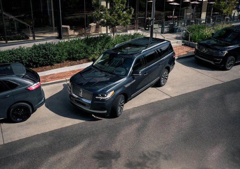 A 2022 Lincoln Navigator SUV is being parallel parked between two vehicles on a downtown street outside of a luxury hotel | Stevens Creek Lincoln in San Jose CA