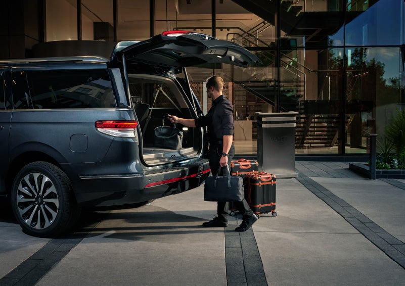 A valet is unloading luggage from the rear cargo area of a 2022 Lincoln Navigator SUV | Stevens Creek Lincoln in San Jose CA