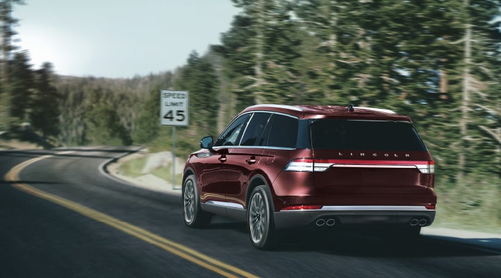 A 2024 Lincoln Aviator® SUV is being driven on a winding mountain road | Stevens Creek Lincoln in San Jose CA
