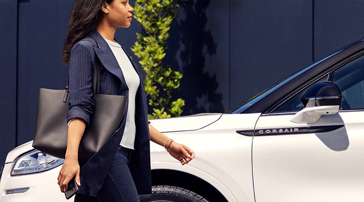 A woman approaches a 2024 Lincoln Corsair® SUV while holding a smartphone. | Stevens Creek Lincoln in San Jose CA