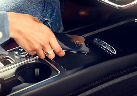 A smartphone is is being placed on the wireless charging pad in the front center console cubby. | Stevens Creek Lincoln in San Jose CA