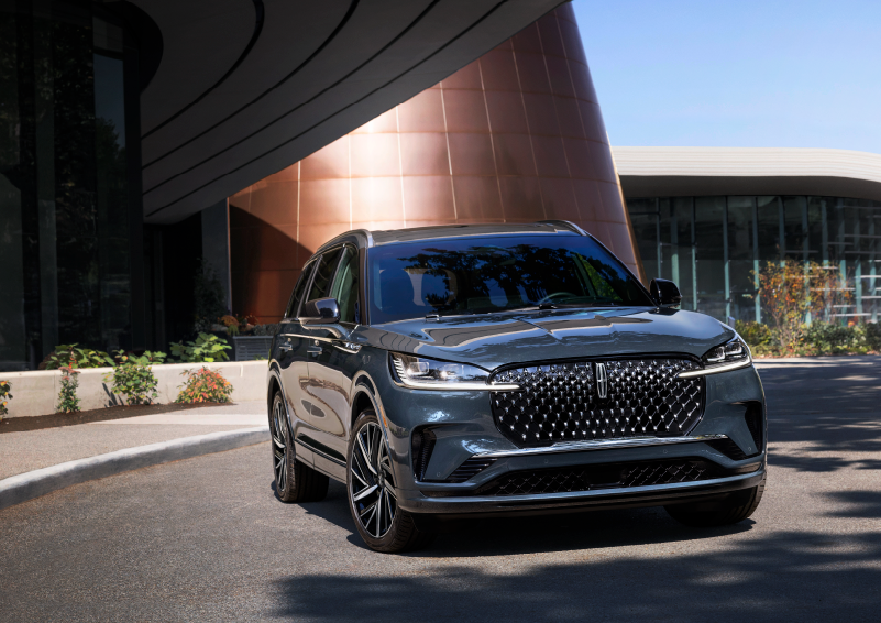 A gray 2025 Lincoln Aviator® SUV is parked outside a modern building with the sun shining. | Stevens Creek Lincoln in San Jose CA
