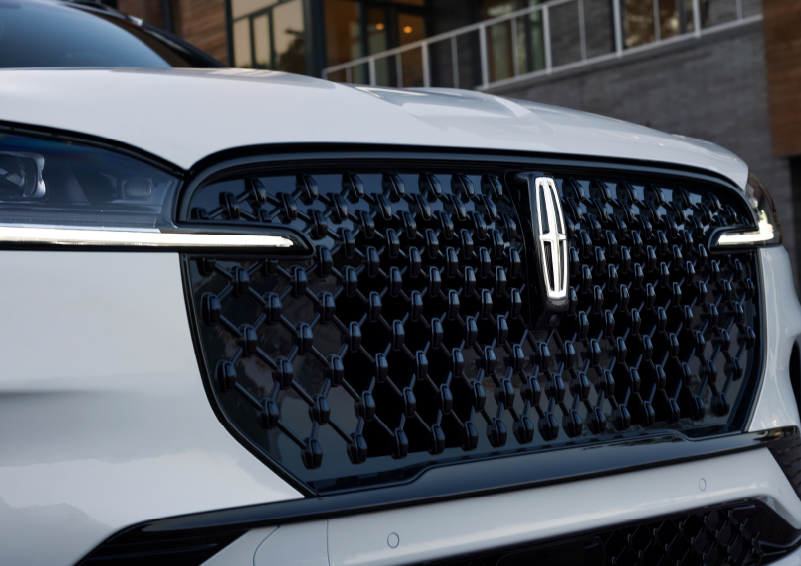 The black grille of a white 2025 Lincoln Aviator® SUV is shown with its fog lights on. | Stevens Creek Lincoln in San Jose CA