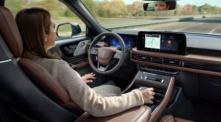 A 2026 Lincoln Aviator® SUV is being driven hands-free on a highway near a forest | Stevens Creek Lincoln in San Jose CA