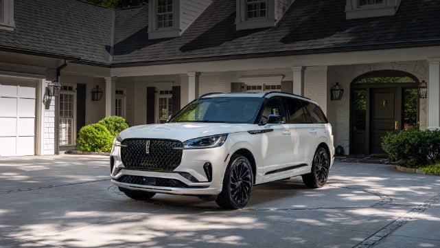 A white 2026 Lincoln Aviator® SUV is parked in the driveway of a luxury home. | Stevens Creek Lincoln in San Jose CA