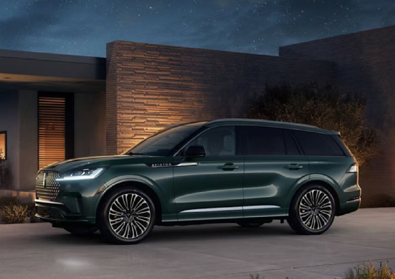 A green 2027 Lincoln Aviator® SUV is parked outside a contemporary home. | Stevens Creek Lincoln in San Jose CA