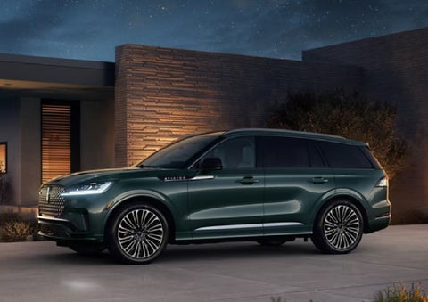 A green 2027 Lincoln Aviator® SUV is parked outside a contemporary home. | Stevens Creek Lincoln in San Jose CA