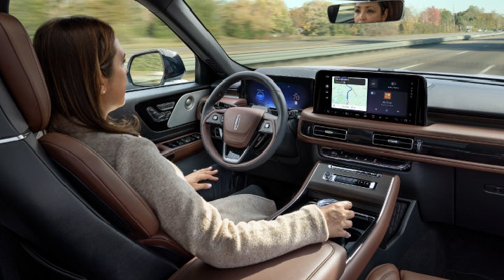 A 2027 Lincoln Aviator® SUV is being driven hands-free on a highway lined with trees. | Stevens Creek Lincoln in San Jose CA