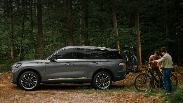 A father and son load e-bikes on a bike rack attached to a 2027 Lincoln Aviator® SUV. | Stevens Creek Lincoln in San Jose CA